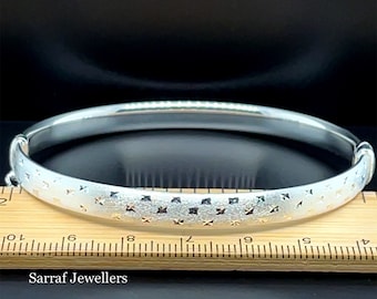 May include: A silver bangle bracelet with a textured surface and a pattern of small squares. The bracelet is about 9 inches in diameter.