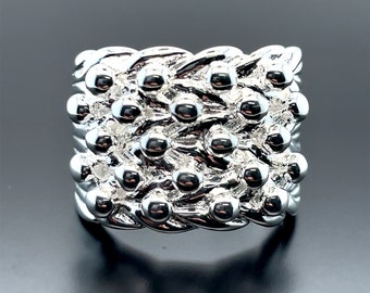 May include: A silver ring with a textured design featuring a repeating pattern of small, round beads.