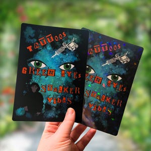 May include: Two black rectangular cards with the words "Tattoos", "Green Eyes", "Stalker Vibes" and a tattoo machine illustration. The cards have a blue and green background with green eyes and a silhouette of a person.