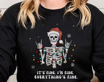 May include: Black sweatshirt with a skeleton wearing a Santa hat and Christmas lights. The text on the sweatshirt reads "It's fine. I'm fine. Everything's fine."