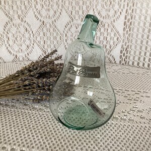 Peut inclure: Une bouteille en verre vert clair en forme de poire avec une étiquette "Pot Pourri". Un bouquet de lavande séchée est à côté de la bouteille. La bouteille a une forme unique et une esthétique vintage.