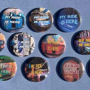 Puede incluir: Una colección de once chapas redondas, cada una con una escena fotográfica única de una atracción de parque temático y el texto "MY RIDE IS HERE" impreso en varios colores y fuentes en el centro de cada diseño individual de la chapa.