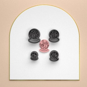 May include: Five black and white crystal ball cookie cutters with a crescent moon design. One cookie cutter is pink.