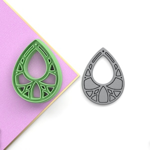 Könnte beinhalten: Ein Paar tropfenförmige Ohrringe mit geometrischem Design. Die Ohrringe sind aus hellgrünem Kunststoff und grauem Kunststoff.