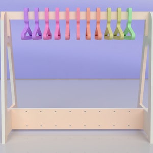 May include: A white wooden coat rack with a light pink shelf and a row of colourful plastic hangers. The hangers are in shades of purple, pink, orange, yellow, and green.