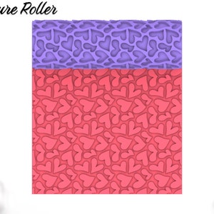 May include: A pink and purple texture roller with a repeating heart pattern. The roller is designed for use with fondant, clay, or other crafting materials. "Texture Roller" is printed on the top of the image.