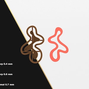 Puede incluir: Dos formas abstractas, una marrón y otra roja, se muestran sobre un fondo blanco. Las formas son similares en diseño, pero la forma marrón tiene un diseño más intrincado. Las formas están disponibles en formato STL para impresión 3D.