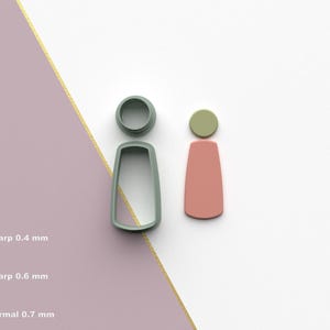 May include: Two earring-shaped polymer clay cutters, one in a light green color and the other in a dusty rose color. The cutters are next to a gray cutter. The image also shows the text "Sharp 0.4 mm", "Sharp 0.6 mm", and "Normal 0.7 mm".