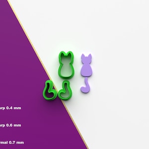 Peut inclure: Trois emportes-pièces en plastique vert en forme de chats. Deux des emportes-pièces représentent un chat assis avec sa queue enroulée autour de ses pattes. Le troisième emporte-pièce représente un chat debout avec sa queue droite derrière lui. Il y a aussi un emporte-pièce en plastique violet en forme de chat debout avec sa queue droite derrière lui.