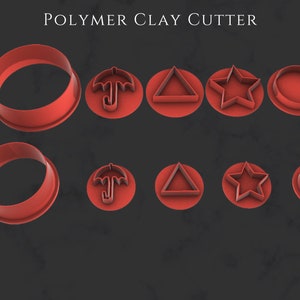 Puede incluir: Conjunto de 10 cortadores de arcilla polimérica roja, que incluyen dos cortadores redondos, dos cortadores de paraguas, dos cortadores triangulares, dos cortadores de estrellas y dos cortadores circulares. Los cortadores están dispuestos en dos filas de cinco. El cortador redondo más grande mide 40,00 mm de diámetro, y el cortador redondo más pequeño mide 30,00 mm de diámetro.