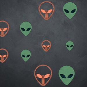 Puede incluir: Un fondo negro con múltiples siluetas de cabezas de extraterrestres. Algunas son verdes y otras son naranjas.