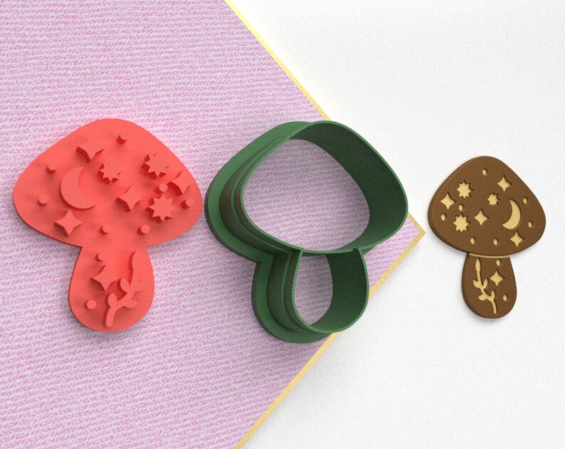 Pode incluir: Tr&ecirc;s cortadores de biscoitos em forma de cogumelo. Um &eacute; vermelho com um desenho de lua e estrelas, outro &eacute; verde e o &uacute;ltimo &eacute; marrom com um desenho de lua e estrelas.