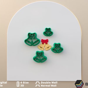 May include: Set of five green Christmas bell cookie cutters with red bows. The cutters are in different sizes and are made of plastic.