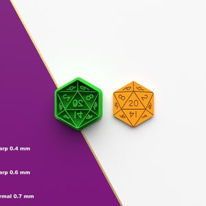May include: Two polyhedral dice, one green and one orange, are displayed against a white and purple background. The green die has white numbers, and the orange die has brown numbers. The image also includes text indicating different sharpness levels.