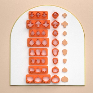 May include: A set of 10 orange plastic cookie cutters in various autumnal shapes, including pumpkins, acorns, leaves, and mushrooms. The cutters are arranged in two rows on a white background.