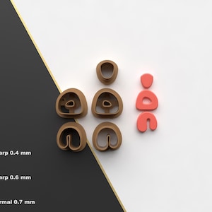 Puede incluir: Colección de cortadores de galletas impresos en 3D de color marrón y coral. Los cortadores tienen varias formas, incluyendo la letra "D" y otras formas abstractas. La imagen también incluye texto que indica diferentes afilados de borde de corte: 0,4 mm, 0,6 mm y 0,7 mm.
