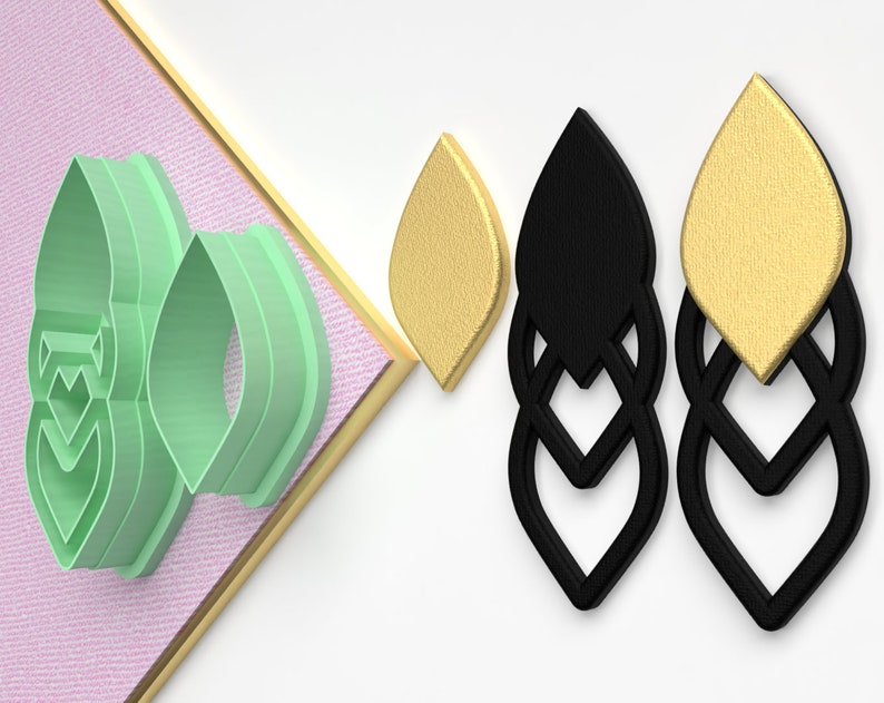 May include: A set of three green plastic cookie cutters shaped like a leaf with a decorative pattern. The cutters are shown next to two pairs of earrings, one pair is black and the other is gold.