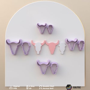 Puede incluir: Un conjunto de nueve cortadores de galletas de plástico morado y rosa con forma de cráneos de toro. Los cortadores están dispuestos en semicírculo sobre un fondo blanco.