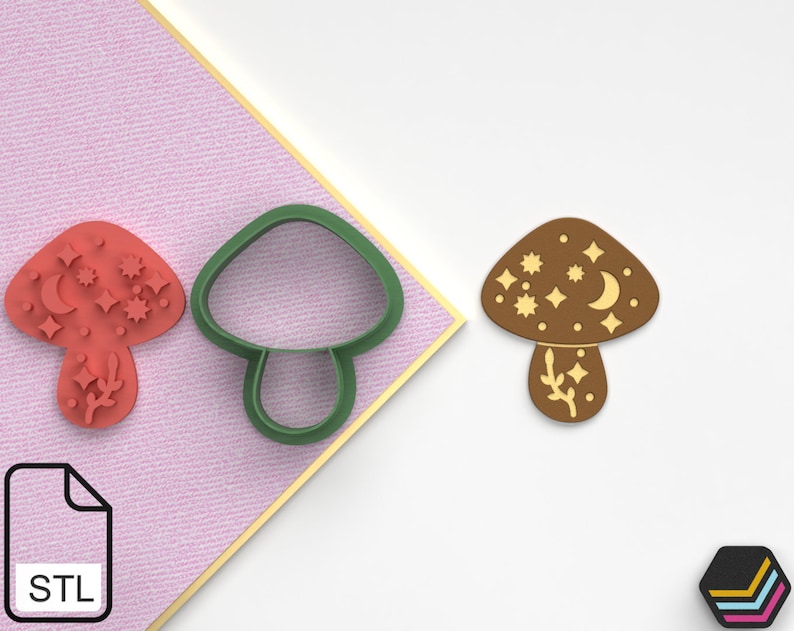 Pode incluir: Um cortador de biscoitos de cogumelo marrom com um design de lua e estrelas. O cortador est&aacute; ao lado de um biscoito de cogumelo vermelho com o mesmo design.