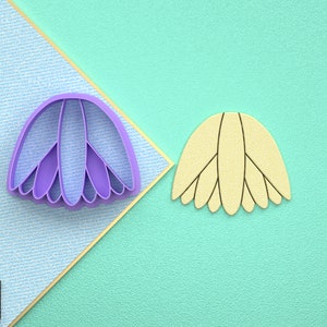 May include: Two cookie cutters, one purple and one yellow, shaped like a flower with multiple petals.