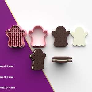 May include: A collection of ghost-shaped cookie cutters and a cookie. The cutters are pink and the cookie is brown with white filling. The cutters have different edge sharpnesses: 0.4 mm, 0.6 mm, and 0.7 mm.