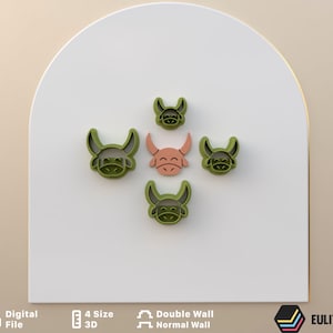 May include: Five green plastic cookie cutters shaped like a bull's head. The cutters are arranged in a circle with a smaller cutter in the center. The center cutter is a light pink color.