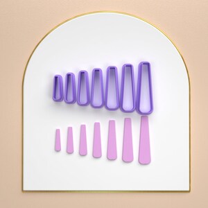 May include: A set of 10 purple and pink nail art stencils in various sizes. The stencils are arranged in a row on a white background.