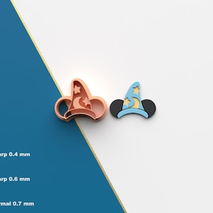 May include: Two 3D printed cookie cutters, one in light blue and one in peach, shaped like Mickey Mouse ears with a wizard hat on top. The hat has a crescent moon and stars on it. The cutters are on a white background.