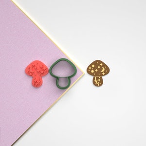 Pode incluir: Um conjunto de tr&ecirc;s cortadores de biscoitos de cogumelo impressos em 3D. Os cortadores t&ecirc;m a forma de um cogumelo com uma lua crescente e estrelas no chap&eacute;u. Os cortadores s&atilde;o verdes, marrons e vermelhos.