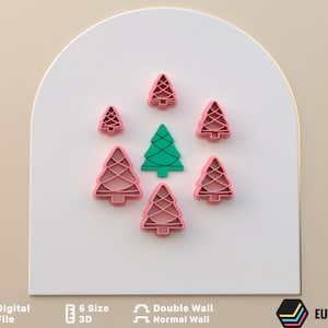 Puede incluir: Un juego de seis cortadores de galletas de árbol de Navidad de color rosa, con un cortador de galletas de árbol de Navidad verde en el centro.