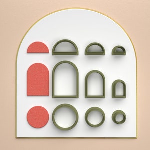 Puede incluir: Una pizarra blanca con marco dorado, que presenta una variedad de formas geométricas en tonos de verde y rojo. Las formas incluyen círculos, arcos y rectángulos.