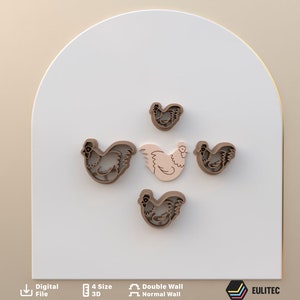 Puede incluir: Cinco cortadores de galletas con forma de pollo. Cuatro son marrones y uno es rosa. Los cortadores están dispuestos en círculo sobre una superficie blanca.