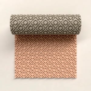 May include: A textured roller with a geometric pattern is shown partially rolled over a sheet of material. The roller is a light gray color, and the material is a soft peach color. The pattern is a series of interlocking squares and diamonds.