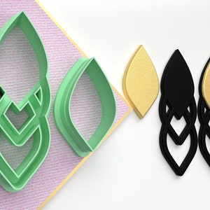 May include: A set of three green plastic cookie cutters shaped like a leaf. The cutters are shown next to two pairs of earrings, one pair is black and the other is gold.
