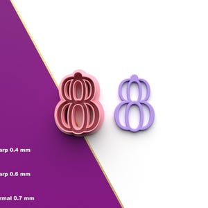 以下が含まれることがあります： 数字の8の形をした2つのプラスチック製のクッキーカッター。1つはピンク、もう1つは紫です。ピンクのカッターはエッジが太くなっています。画像は白と紫の背景にあります。