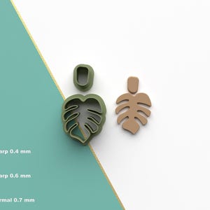 Könnte beinhalten: Ein Set aus drei blattförmigen Polymer Clay Ausstechern in Grün und Beige. Die Ausstecher sind für das Basteln konzipiert und umfassen ein großes Blatt, ein kleines Blatt und einen Stiel. Das Bild zeigt auch das STL-Dateisymbol.