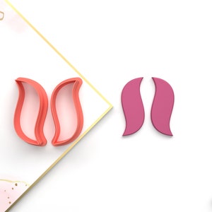 May include: Two pink and two red plastic cookie cutters shaped like a tulip. The cutters are on a white background.