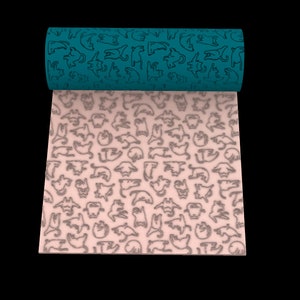 Peut inclure: Un tissu roulé de couleur turquoise avec un motif répétitif de chats noirs. Le tissu est déroulé pour révéler un tissu rose clair avec le même motif de chats noirs.