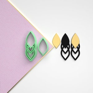 May include: A set of three layered earring designs in green, black, and yellow. The earrings are in the shape of a leaf with a geometric pattern. The design is shown on a white background.