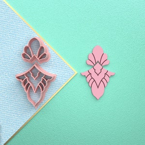 Op de afbeelding: Een roze 3D-geprint ontwerp met ingewikkelde details. Het ontwerp is een symmetrisch patroon met een puntige bovenkant en een afgeronde onderkant. Het ontwerp wordt in twee weergaven getoond, één met de voorkant naar de kijker en de andere met de achterkant naar de kijker. Het ontwerp is gemaakt van een glad, glanzend materiaal.