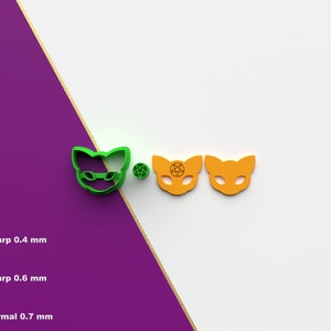 Könnte beinhalten: Ein grüner Katzen-Ausstecher mit Sonnenbrille, eine kleine grüne Kugel und zwei orangefarbene Katzen-Ausstecher. Das Bild zeigt auch ein Diagramm mit dem Text "Sharp 0,4 mm", "Sharp 0,6 mm" und "Normal 0,7 mm". Der Hintergrund ist weiß und lila.