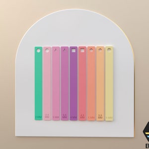 May include: A set of eight colorful plastic strips with different sized holes, ranging from 2 mm to 6 mm. The strips are arranged in a row on a white surface.