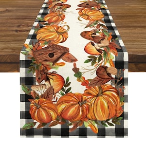 Peut inclure: Chemin de table sur le thème de l'automne, avec un panneau central crème orné de citrouilles, de feuilles et de nichoirs à l'aquarelle. Les bords sont encadrés d'un motif à carreaux noir et blanc, créant une esthétique festive et saisonnière.