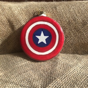 May include: A red, white, and blue Christmas ornament shaped like Captain America's shield.