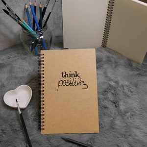 think positive | Handbeschriebenes A5-Notizbuch mit Spruch | schwarze Schrift | Kraftpapiercover | 100 cremeweiße Blätter | Spiralbindung