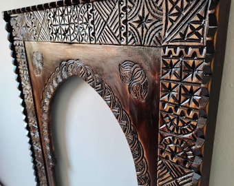 May include: A dark brown wooden picture frame with intricate carved designs. The frame has an arched opening and a decorative border.