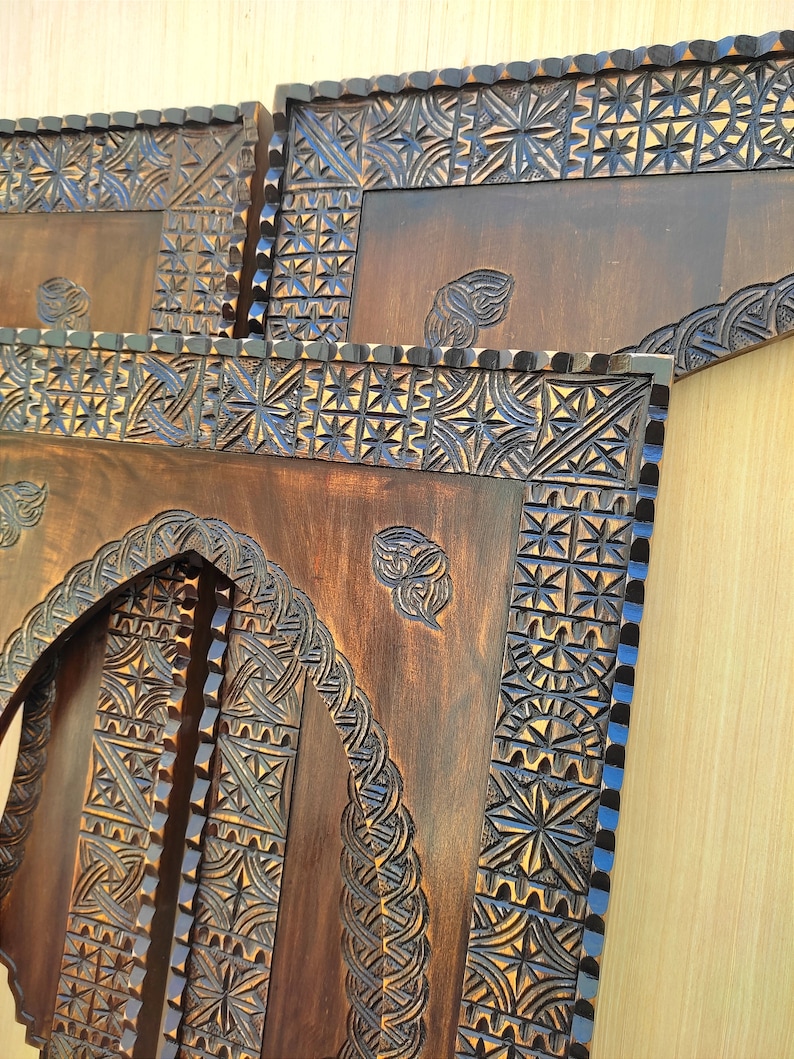 May include: Close-up of intricately carved wooden panels. The panels feature detailed geometric and floral patterns, with a dark brown finish. The carvings are highlighted with a contrasting blue color, adding depth and visual interest to the artwork.