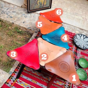 May include: Six colorful leather poufs in the shape of a triangle, arranged in a stack. The poufs are decorated with intricate patterns and are numbered 1 through 6. The poufs are sitting on a red and white patterned rug. The question "What is Your Favorite Color?" is written in white text on a pink background at the bottom of the image.