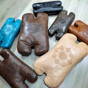 May include: Assortment of six leather cushions in various colors and patterns. The cushions are all in the shape of a human torso with two arms. The cushions are made of leather and have intricate designs.