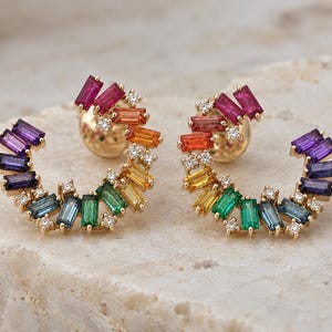Pode incluir: Um par de brincos de ouro em forma de meia-lua, com um gradiente arco-íris de pedras preciosas de corte baguette em roxo, azul, verde, amarelo, laranja e vermelho, acentuados com pequenos diamantes brancos redondos em armação de ouro.